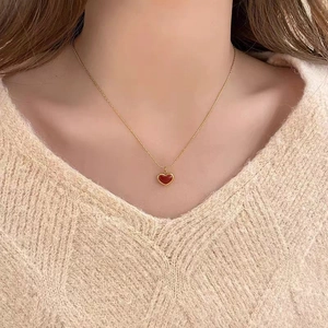 Collier élégant en acier titane doré avec un petit pendentif coeur rouge sur un mannequin