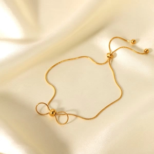 Bracelet ajustable à nœud doré élégant sur un fond de tissu en soie crème lisse