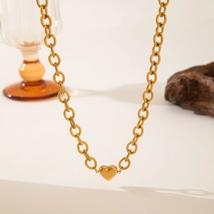 Golden chunky oval link chain necklace featuring a polished heart pendant on a wooden prop