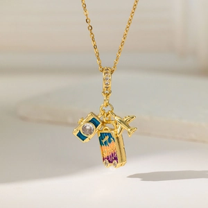 Collier de voyage doré avec pendentifs appareil photo bleu, valise et avion en zircons
