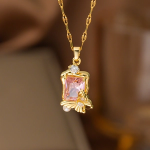 Gros plan sur un collier doré orné d'un cristal rose et d'un pendentif papillon