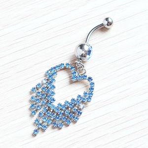 Silver belly button ring featuring a blue rhinestone heart pendant on wood background