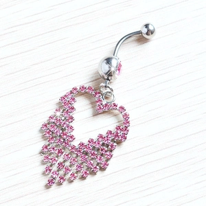Polished heart tassel belly button ring with pink rhinestones on a wooden surface