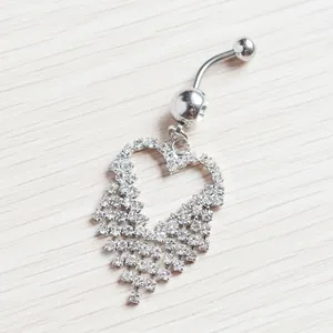 Macro shot of silver heart belly ring with tassel rhinestones on wood texture