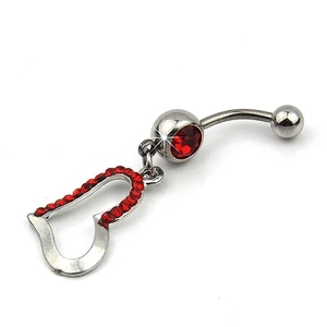 Macro shot of curved belly button ring with heart pendant and sparkling red rhinestones