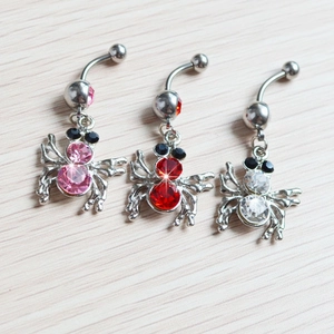 Detalle de piercings de ombligo de araña con cristales rosas, rojos y blancos