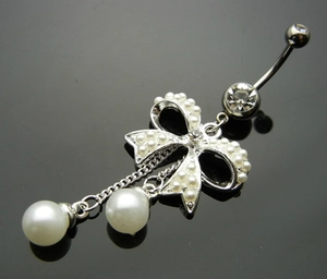 Macro detail of silver bow belly ring with embedded pearls and dangling bead charms