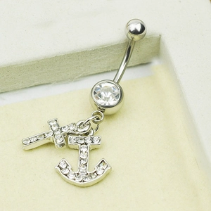Detailed close-up of a silver belly ring with diamond-encrusted cross and anchor charms