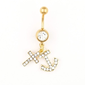 Macro detail of golden belly ring with rhinestone-encrusted cross and anchor charms
