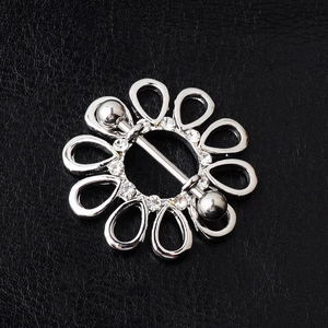 Detail eines floralen Nippelpiercings mit funkelnden Kristallen auf schwarzem Lederhintergrund