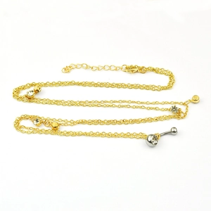 Gouden buikketting met fonkelende strassteentjes en een zilveren navelpiercing