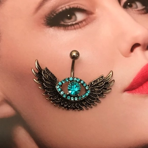 Vintage winged belly button ring with blue crystal eye design on decorative background
