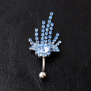 Detailed close-up of sky blue rhinestone belly ring with fanned tassel on leather