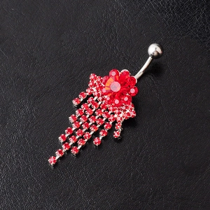 Silver flower belly ring with red crystals and dangling tassels on black leather background