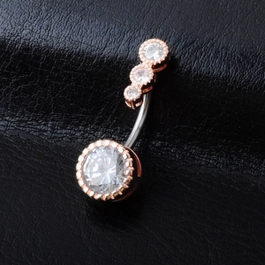 Close-up of rose gold belly ring featuring brilliant zircons on black leather texture