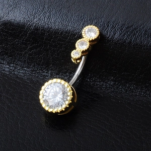 Macro shot of gold navel ring with sparkling cubic zirconia on black leather background