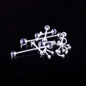 Set di piercing in acrilico trasparente con barre e anelli su sfondo nero riflettente