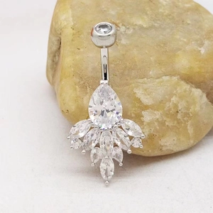Macro shot of silver navel ring with pear-shaped cubic zirconia on yellow stone