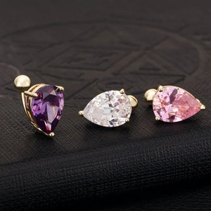 Détail de trois piercings de nombril en forme de poire, couleurs violet, blanc et rose