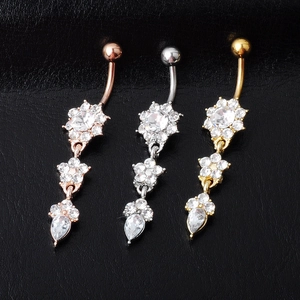 Detailed close-up of three sparkling flower dangle belly rings in gold, silver, and rose gold