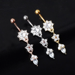 Macro shot of three dangling belly rings with floral motifs and teardrop zircon pendants