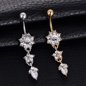 Close-up of polished stainless steel floral belly rings with crystals in gold and silver