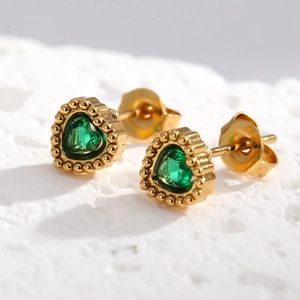 Détails macro de boucles d'oreilles cœur vert zircon avec bordure perlée dorée
