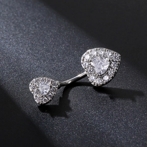 Vista macro di piercing all'ombelico a doppio cuore con zirconi e finitura argento