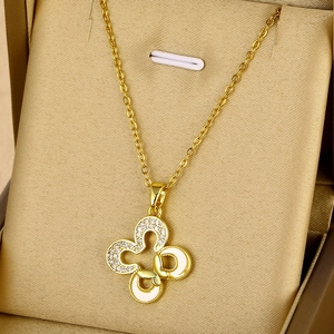 Détail du collier pendentif fleur et papillon doré avec zircons blancs sur du satin