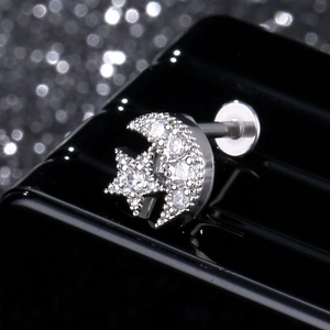 Macro view of star and moon stud earring with pave-set cubic zirconia on a black stand