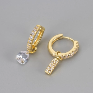 Macro-opname van gouden huggie-oorbellen met druppelzirkonia en pavé-rechthoek hanger