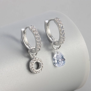 Detail van asymmetrische zilveren oorbellen met peergeslepen zirkonia en micro-pave kristallen