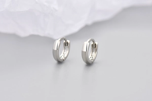 Dettaglio macro di piccoli orecchini a cerchio in argento lucido dal design minimalista
