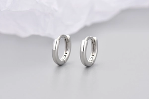 Dettaglio di orecchini a cerchio huggie in argento lucido con finitura minimalista