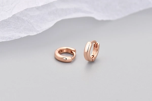 Vista macro di piccoli orecchini a cerchio in oro rosa con chiusura a scatto