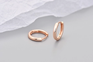 Dettaglio macro di piccoli orecchini a cerchio in oro rosa con finitura lucida e chiusura