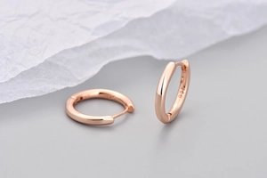 Dettaglio macro di orecchini a cerchio in oro rosa con marchio 925 su metallo lucido