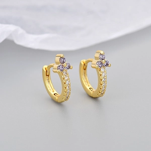 Detailed close-up of golden hoop earrings featuring purple and white cubic zirconia stones