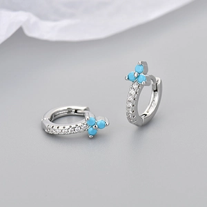 Macro shot of silver huggie earrings with turquoise flower cluster and zircon pavé