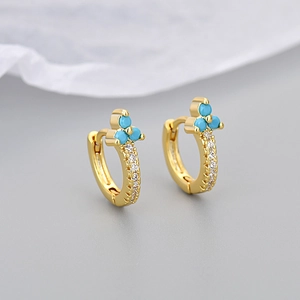 Macro detail of gold flower hoop earrings featuring blue zircon clover and white stones