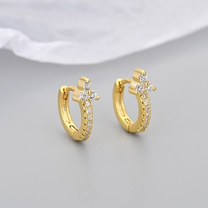 Close-up of gold flower hoop earrings with sparkling zircon stones on a soft fabric base