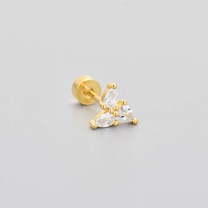 Detailed macro view of gold-plated stud earring with three pear-cut white stones