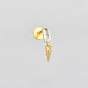 Close-up of golden stud earring with rectangular zircon and sharp spike drop pendant