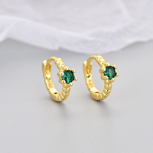 Macro shot of gold-plated S925 silver hoop earrings with green zircon and beaded texture