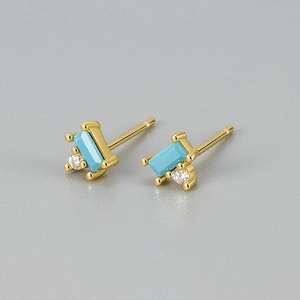 Macro detail of gold-plated earrings featuring rectangular blue stone and zircon studs