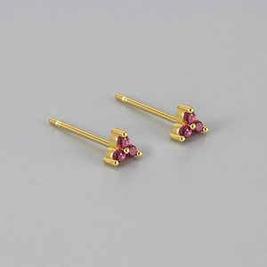 Detailopname van gouden geometrische driehoek oorbellen met ronde roze edelstenen
