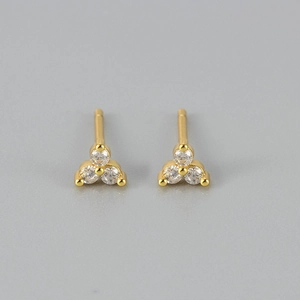 Detailweergave van gouden oorknopjes met een minimalistisch clusterontwerp van drie diamanten