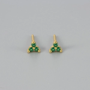 Detail van gouden oorknopjes met drie groene stenen in een minimalistische driehoek