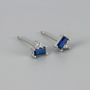 Macro shot of rectangular blue zircon earrings with sparkling round diamond accents