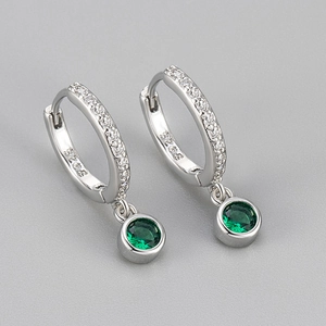 Detailed macro of silver S925 huggie earrings with emerald green zircon pendants